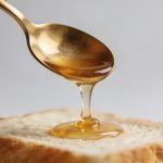 Cuillere de miel doré coulant sur pain