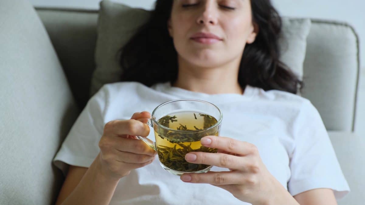 femme allongee sur un canapé tenant une tisane