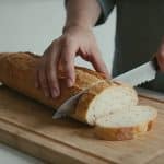 Femme decoupant une baguette sur planche en bois