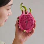Main de femme tenant un fruit du dragon coupe en deux