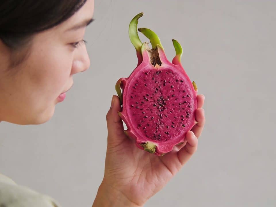 Main de femme tenant un fruit du dragon coupe en deux