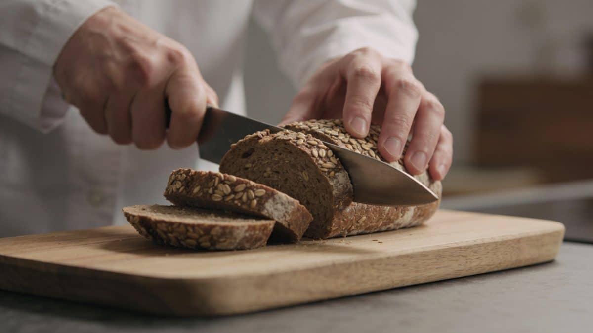 Nutritionniste coupant du pain complet sur planche