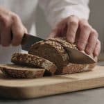 Nutritionniste coupant du pain complet sur planche